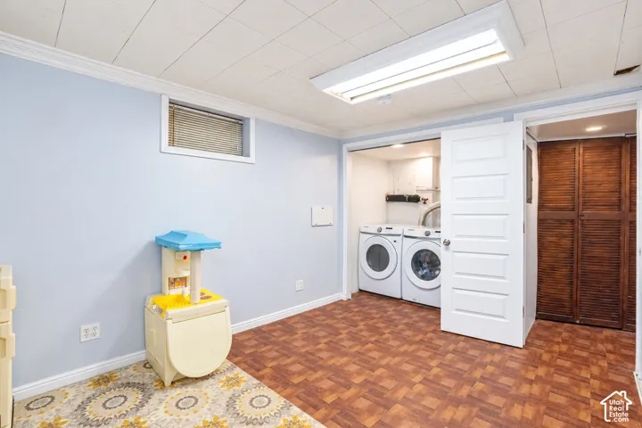 Recessed window, crown molding, laundry area with appliances, white paneled door, and wood louvered bifold doors