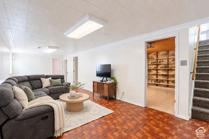 Spacious living area featuring parquet wood-finish flooring, recessed lighting, and crown molding