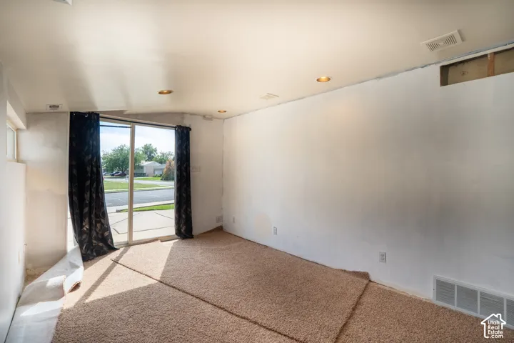 Sliding glass door, recessed ceiling lighting, wall-to-wall carpeting, and white wall finishes