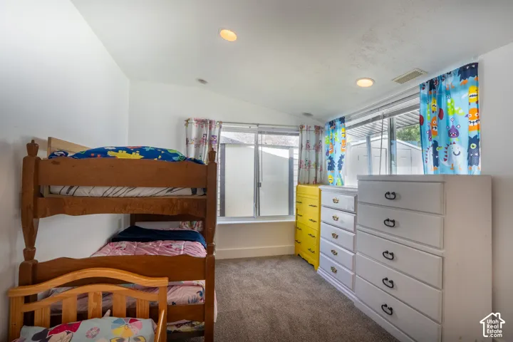 Vaulted ceiling, recessed lighting, carpet flooring, large windows, and white walls