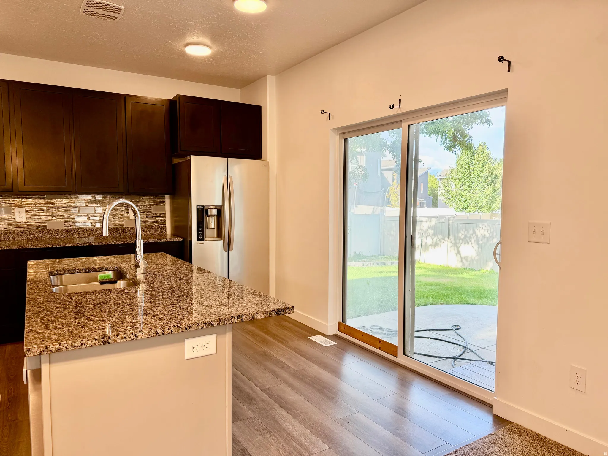 Kitchen featuring a stainless steel refrigerator, granite countertops, and wood-finish flooring