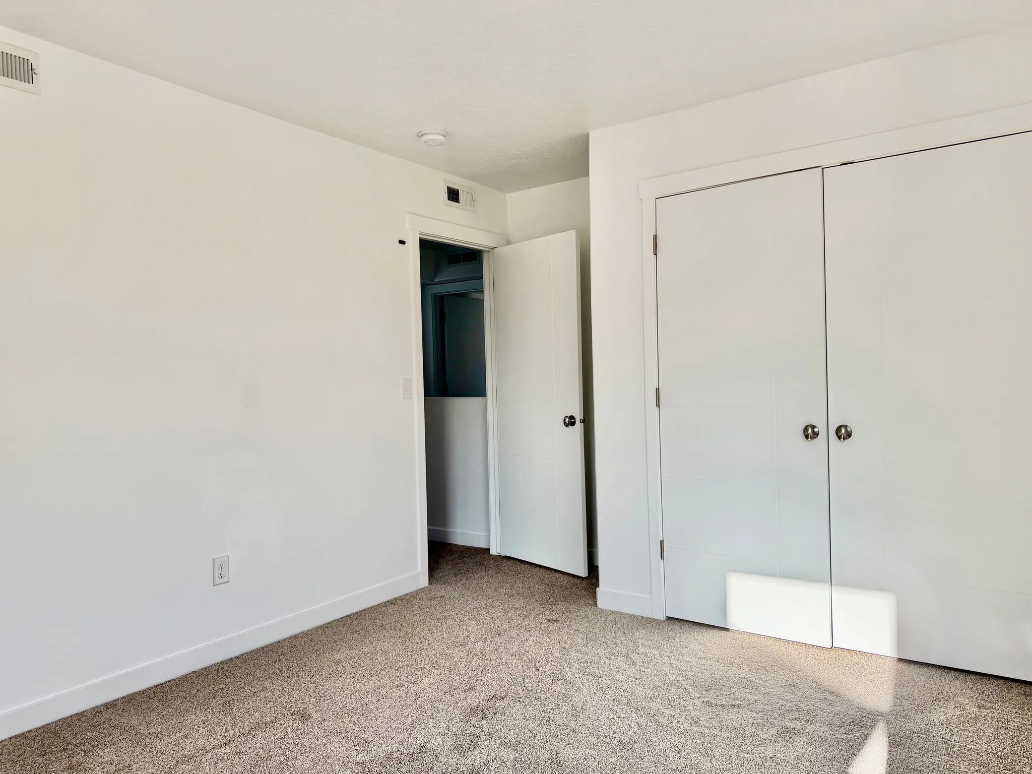 Plush carpeting throughout, white painted walls, and bi-fold closet doors with round hardware