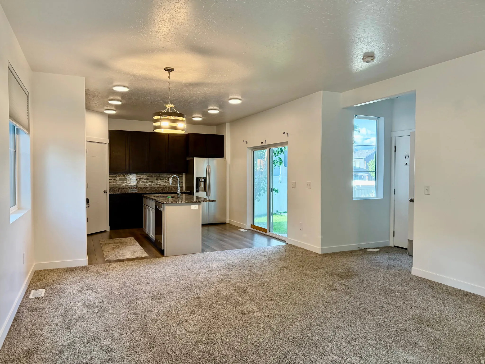 Kitchen featuring dark wood-finish cabinetry, stainless steel appliances, an island with an undermount sink, and recessed lighting