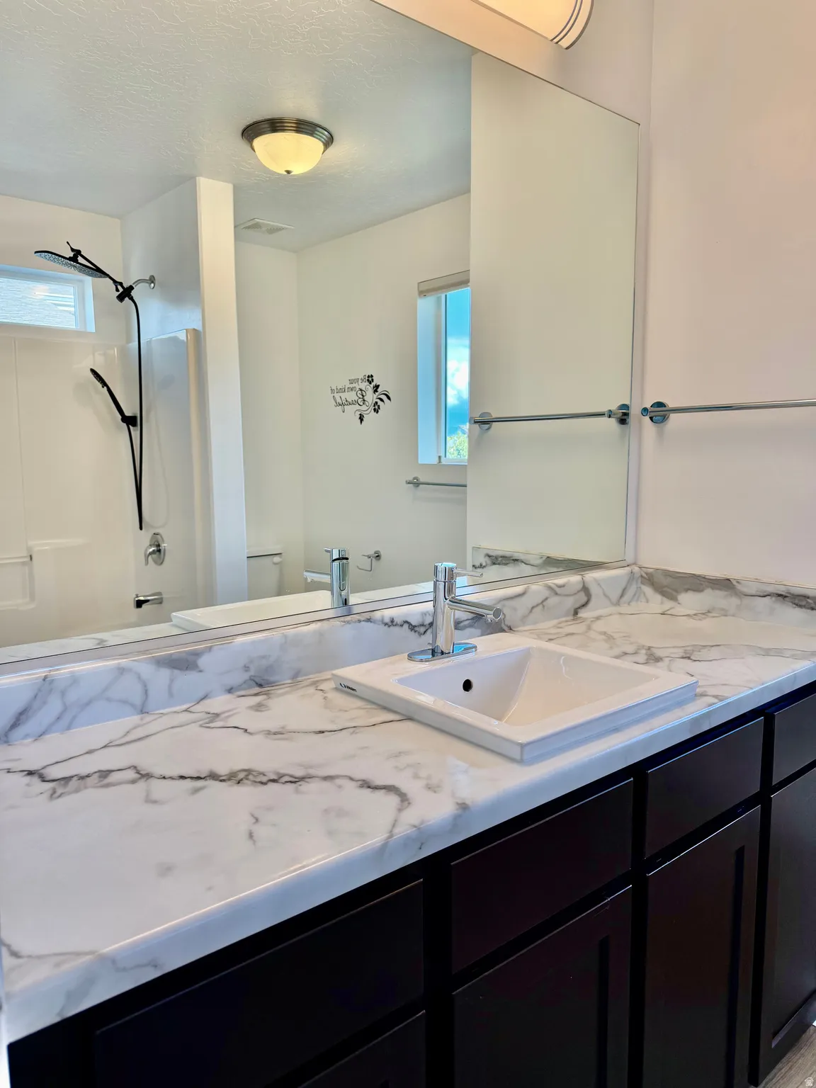 Vanity with a white sink, chrome faucet, and marbled countertop