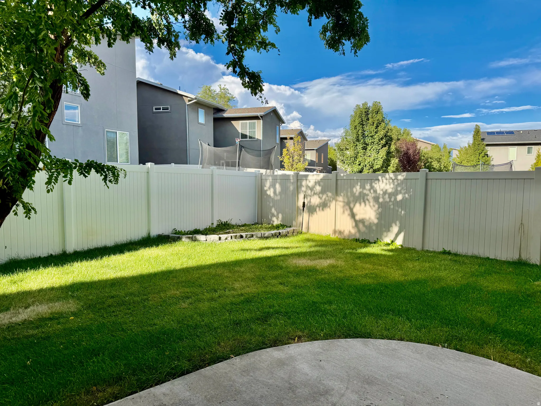 Expansive green lawn with a privacy fence and concrete patio