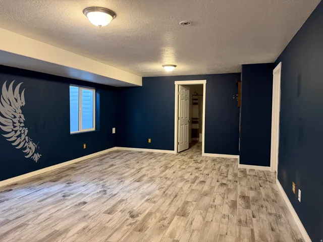 Recessed ceiling lights, wood-finish flooring, white trim, and a window