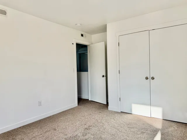 Plush carpeting throughout, white painted walls, and bi-fold closet doors with round hardware
