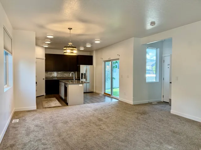 Kitchen featuring dark wood-finish cabinetry, stainless steel appliances, an island with an undermount sink, and recessed lighting