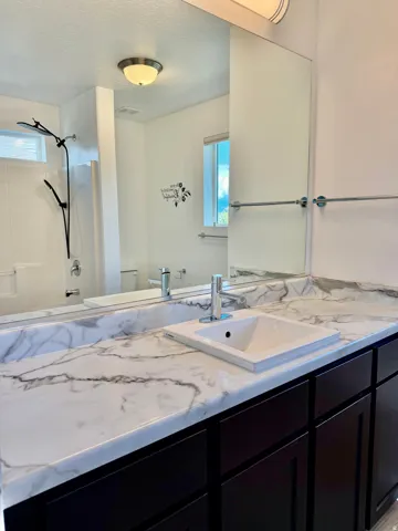 Vanity with a white sink, chrome faucet, and marbled countertop