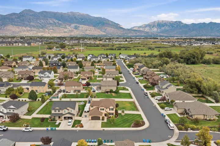 Residential neighborhood with a paved street, manicured lawns, and distant mountain scenery