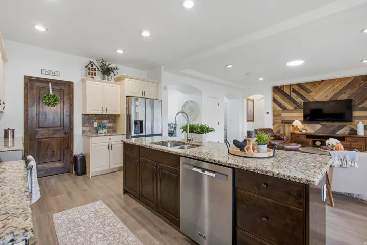 Spacious kitchen island with granite countertops, stainless steel appliances, wood-finish flooring, recessed lighting, and custom wood accent wall