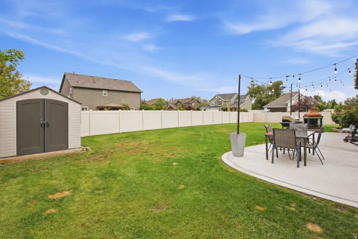 Expansive lawn, privacy fencing, concrete patio, storage shed, string lighting