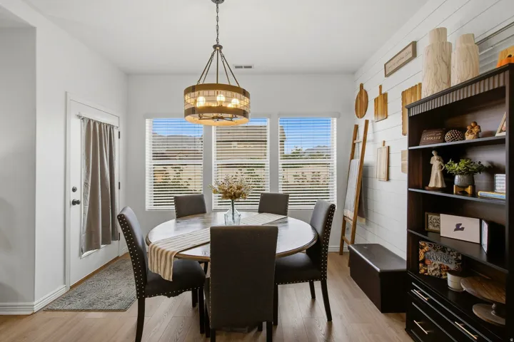 Wood-finish flooring, multiple windows with blinds, a built-in dark wood shelving unit, and a shiplap accent wall