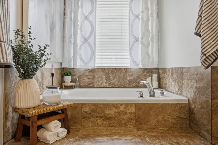 Built-in soaking tub with deck-mounted faucet, surrounded by tiled walls and flooring