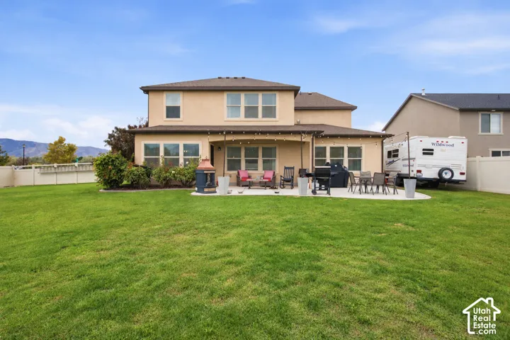 Expansive backyard featuring a large lawn, concrete patio, covered patio area, and perimeter fencing