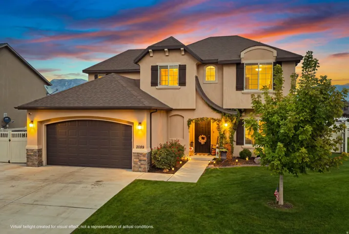 Stucco exterior with stone accents, arched entryway, attached garage, and mature landscaping