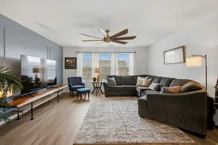 Wood-finish flooring throughout, multi-pane windows with blinds, and an overhead ceiling fan