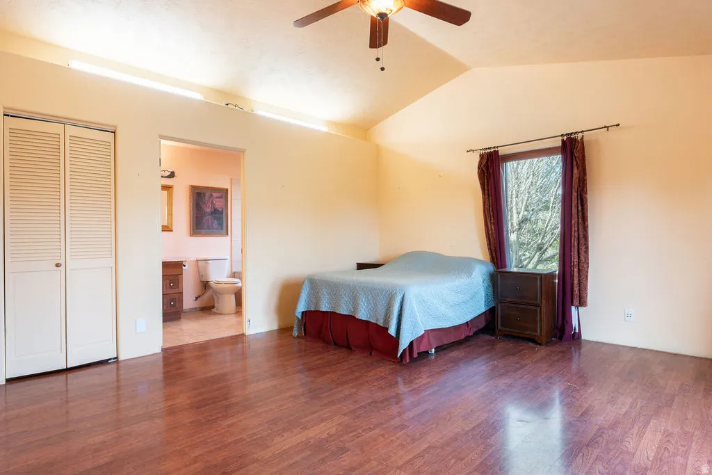 Vaulted ceiling with a ceiling fan, wood-finish flooring, and louvered bifold closet doors