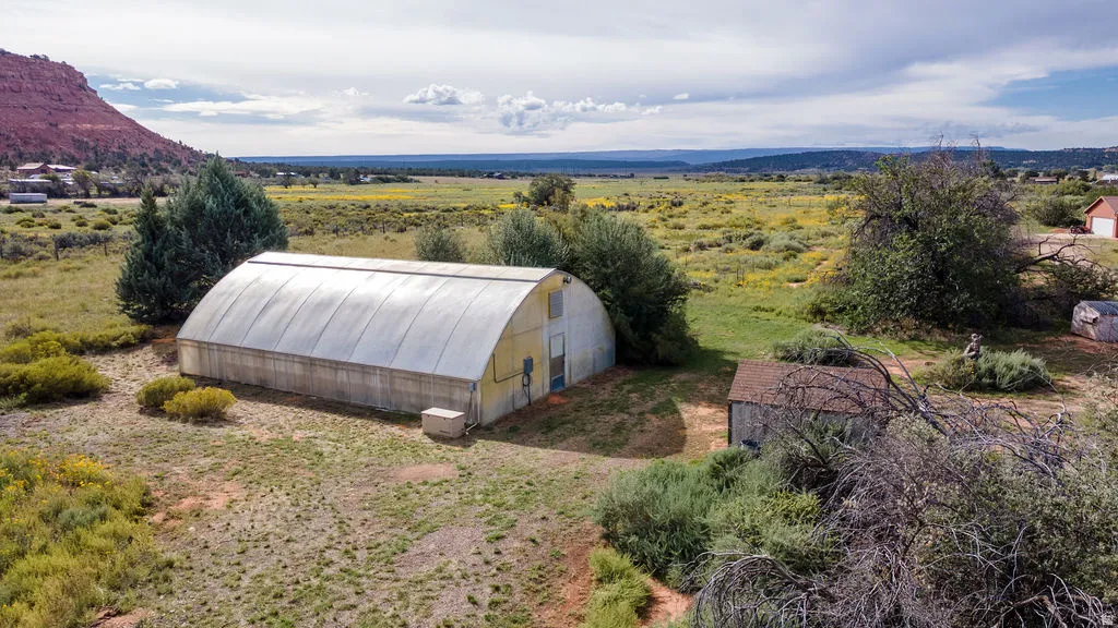 Hoop house structure, outbuilding, and expansive natural landscape