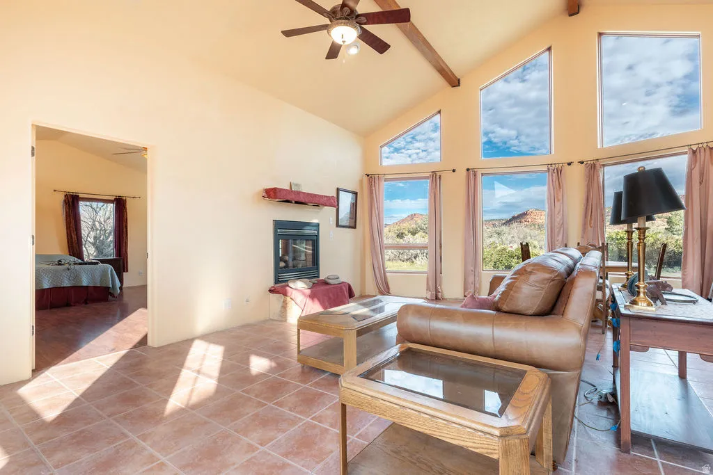 Vaulted ceilings with exposed wood beams, ceramic tile flooring, a built-in fireplace, and expansive windows