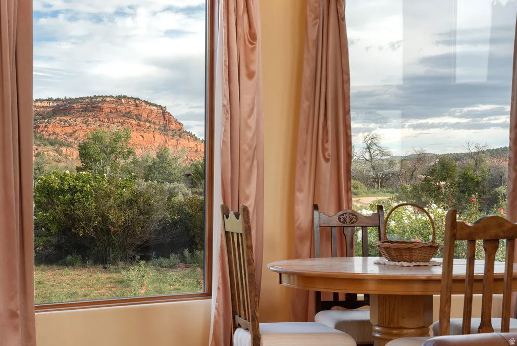 Dining room with expansive windows framing panoramic vistas of red rock formations and native landscaping