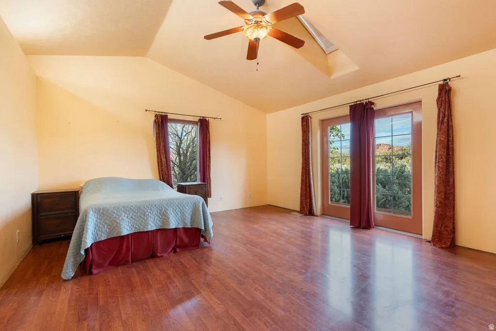 Vaulted ceiling with a ceiling fan, wood-finish flooring, and French doors
