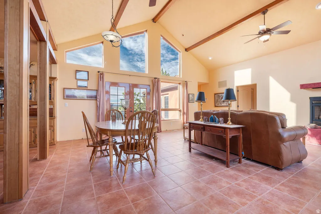 Vaulted ceiling with exposed wood beams, tile flooring, French doors, high transom windows, and a built-in fireplace