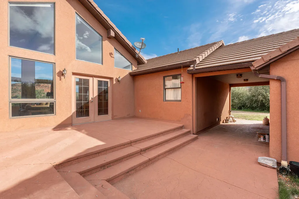 Stucco exterior with multiple large windows, a tiled roof, and a covered breezeway