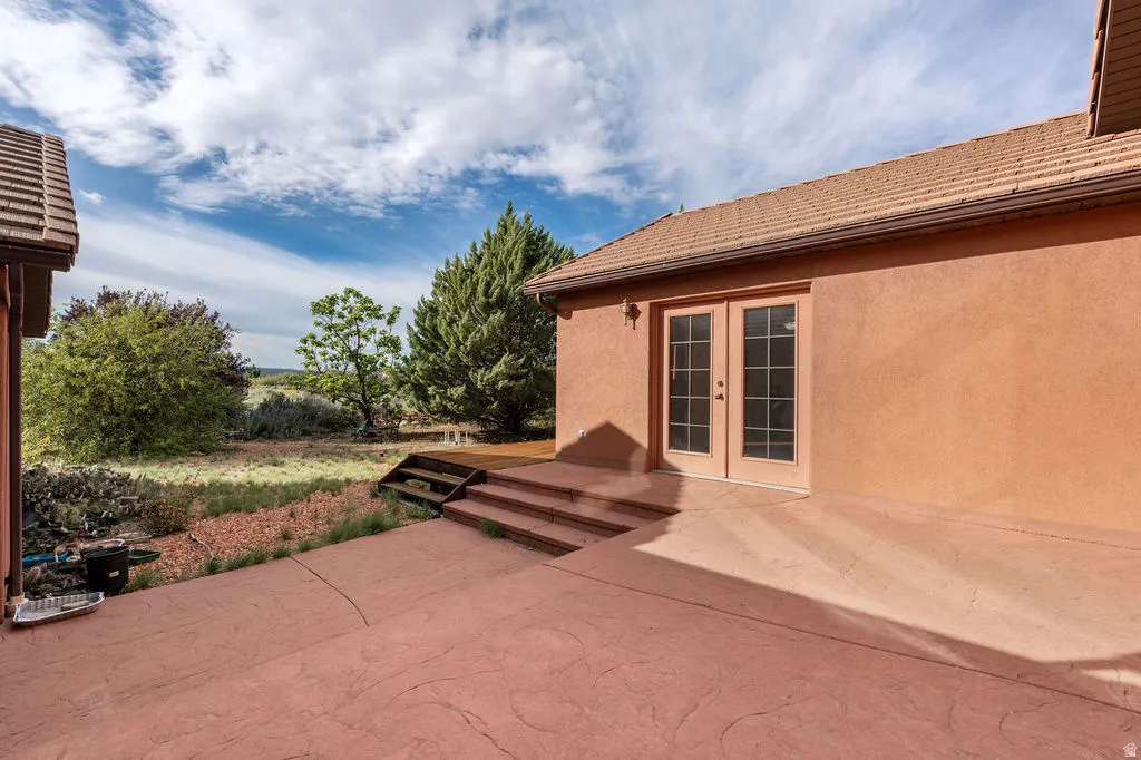 Expansive stamped concrete patio with stepped entry, adjoining a terracotta stucco exterior featuring French doors and multi-pane windows
