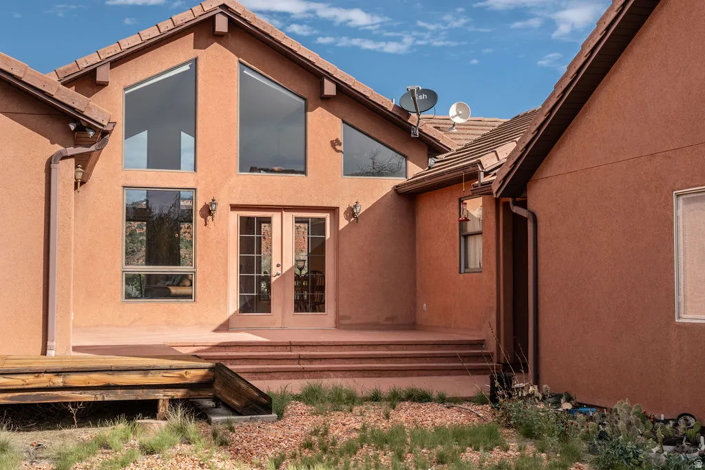 Modern architectural design featuring a striking terra cotta stucco exterior with large multi-pane windows and glass French doors