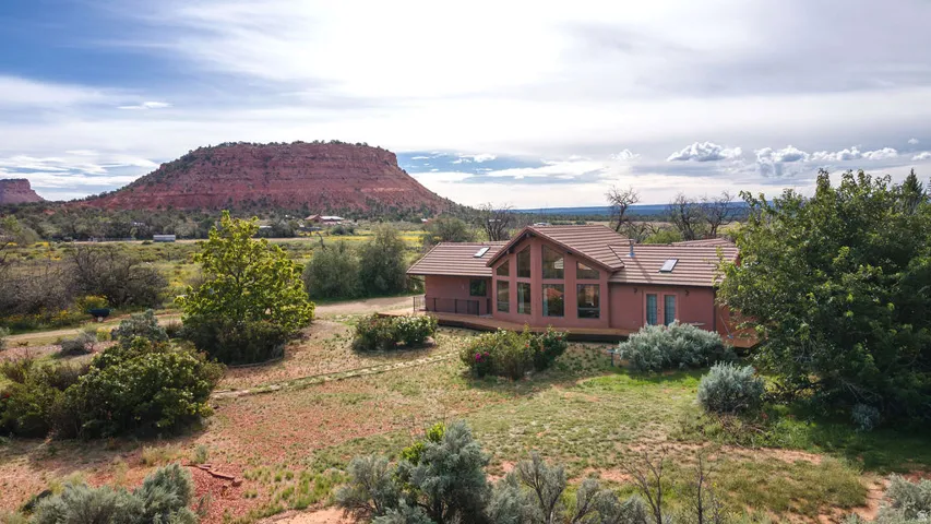 Brick residential home situated on expansive grounds with mature landscaping and native desert vegetation