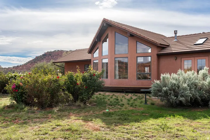 Contemporary residence featuring a striking rust-red exterior with large multi-pane windows, pitched roofline with metal detailing, and horizontal wood siding accents