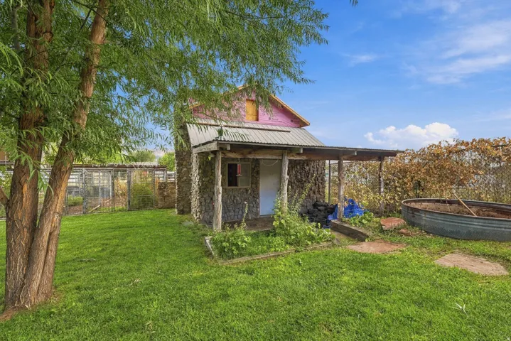 Stone-clad structure with a covered porch, metal roof, and an adjacent greenhouse