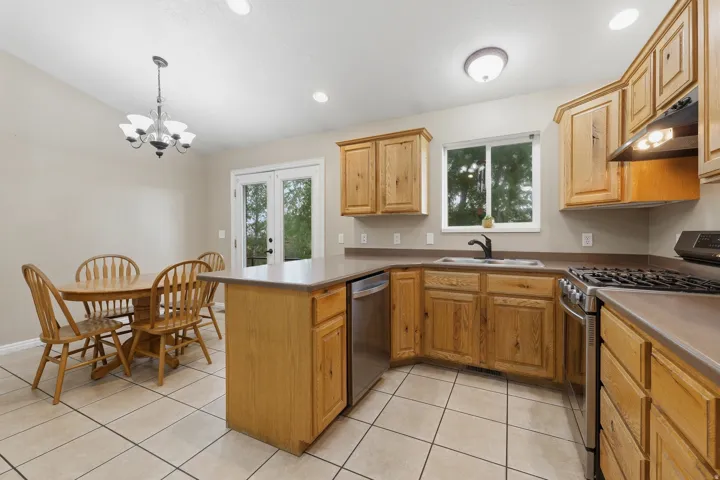 Spacious kitchen featuring warm wood cabinetry, stainless steel gas range, tile flooring, and a central island with countertop workspace