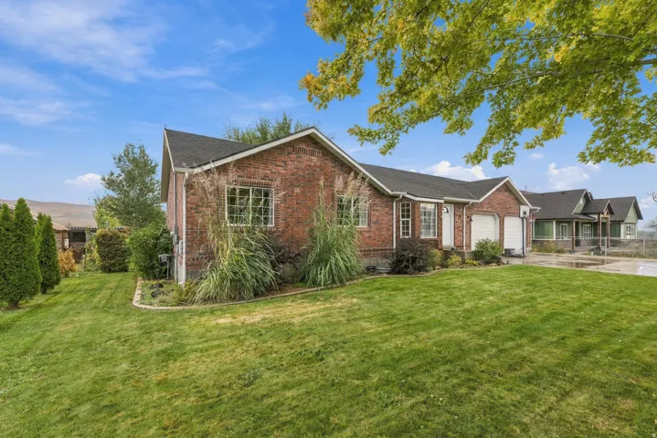 Brick home showcasing a manicured lawn with mature landscaping, including ornamental grasses and established trees