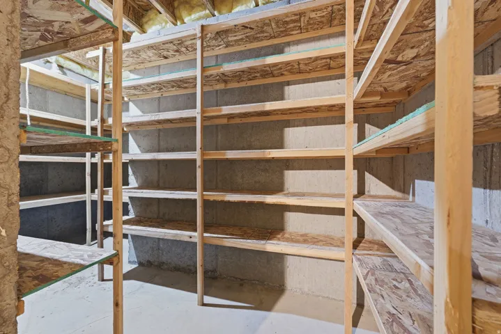 Extensive built-in wood shelving units, concrete block walls, concrete flooring, and exposed ceiling joists