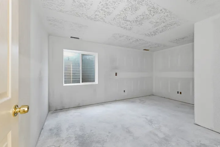 Spacious room featuring fresh drywall construction, recessed ceiling lighting, large window with natural light, and electrical outlets positioned throughout