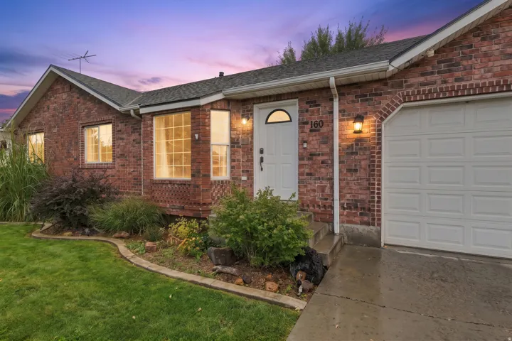 Charming brick ranch home featuring a welcoming front facade with arched transom window, recessed entry lighting, and manicured landscape with ornamental plantings
