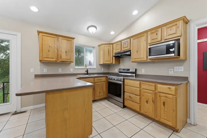 Kitchen featuring wood cabinetry, stainless steel appliances, a built-in microwave, and tile flooring