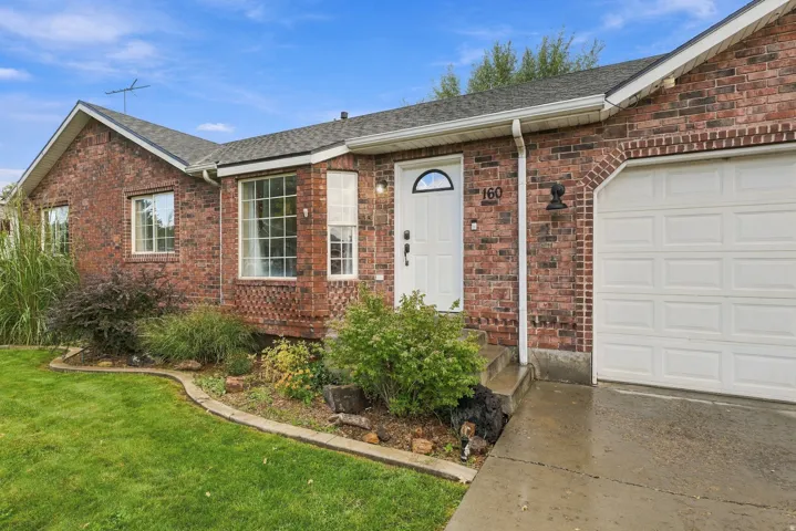 Charming brick ranch home featuring a welcoming front entrance with sidelights, multiple windows flooding the interior with natural light, and a two-car attached garage