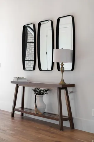 Hardwood flooring with a dark wood-finish console table featuring a slatted lower shelf
