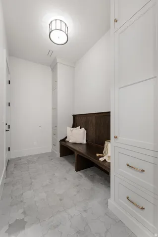 Recessed lighting with a drum light fixture, built-in storage cabinetry with paneling, wood-finish built-in bench, and patterned tile flooring