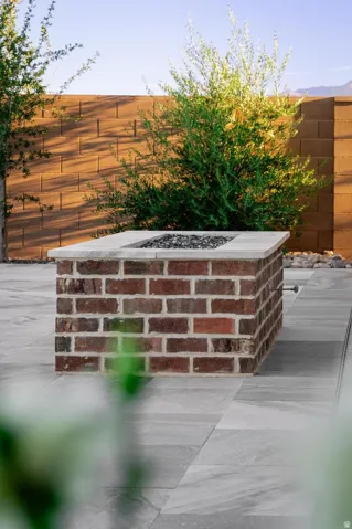 Brick fire pit featuring a light-toned cap, decorative fire glass, and a gas line connection