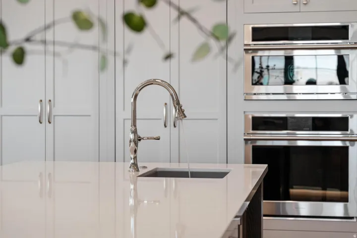 Kitchen island with an undermount sink, gooseneck faucet, and light-toned countertop