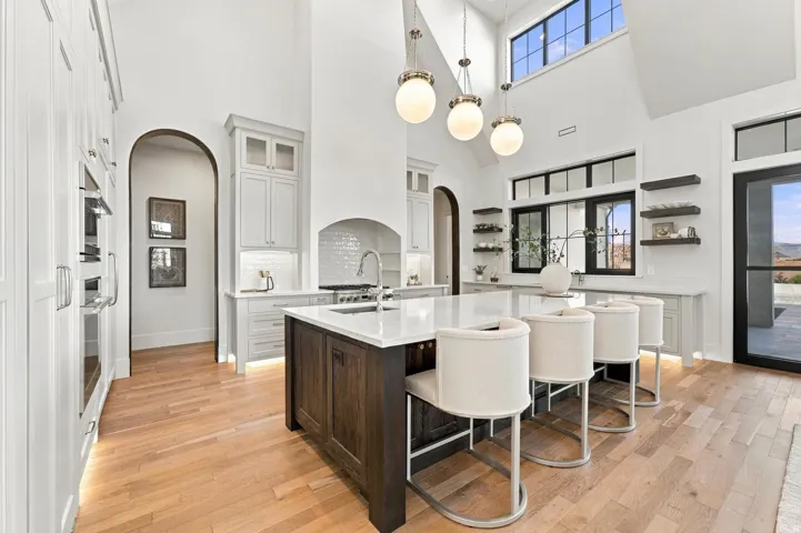 Gourmet kitchen featuring a vaulted ceiling with clerestory windows, integrated appliances, a large center island with seating, and wood-finish flooring