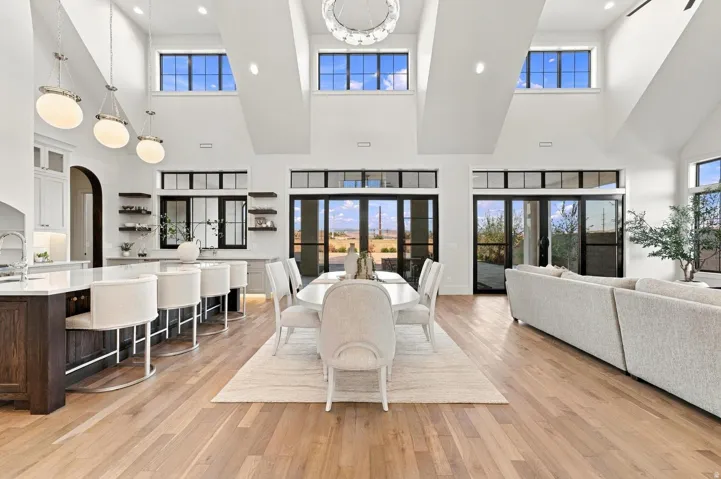 Vaulted ceilings with clerestory windows, wood-finish flooring, two sets of glass patio doors, kitchen island with seating, and integrated shelving