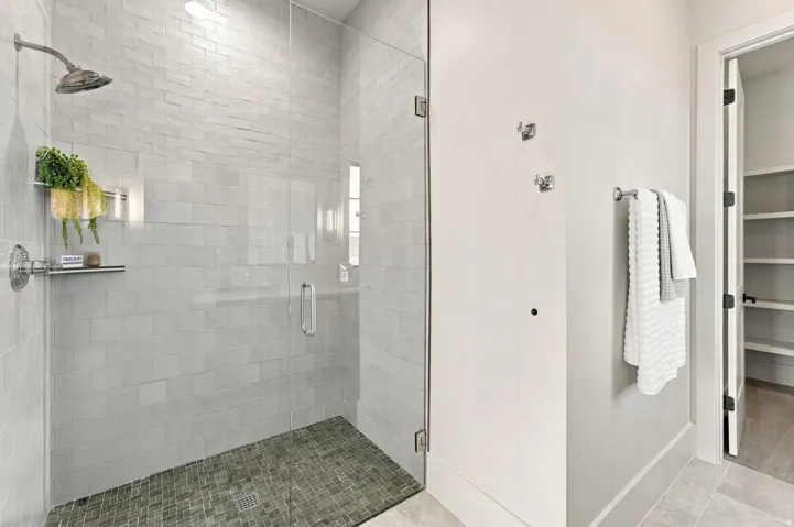 Glass-enclosed shower with subway tile walls and a mosaic tile floor