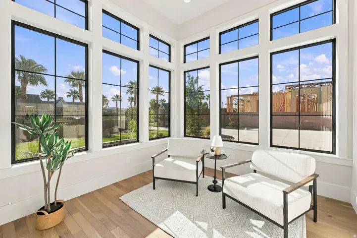 Walls of black-framed windows, light wood-finish flooring, white walls, and white trim