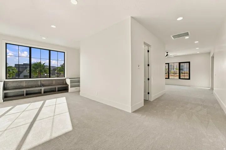 Expansive carpeted room featuring a built-in window bench, grid-pattern windows, recessed lighting, and a ceiling fan