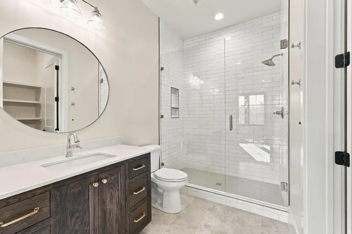 Full glass shower enclosure with subway tile surround and integrated bench